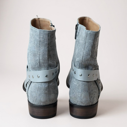 JO Ghost Pair of light blue suede boots with straps on a light gray 