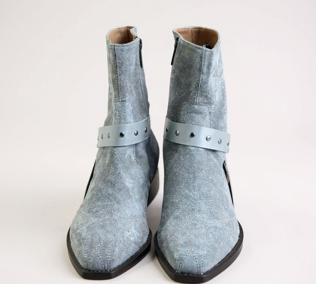 JO Ghost Pair of light blue suede boots with straps on a light gray 