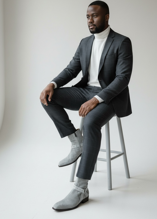 Jo Ghost Man in a gray suit sitting on a stool against a plain 